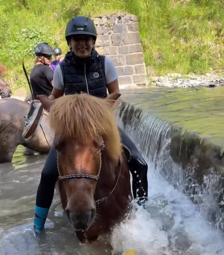 Kinder reiten mit Islandpferden durch einen Bach